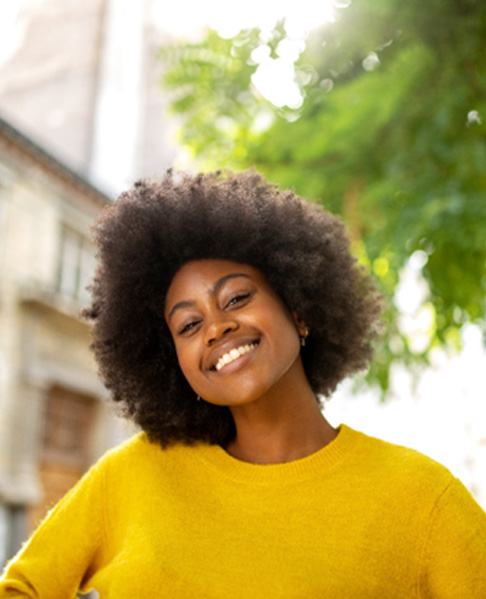 Woman in a yellow sweater smiling outdoors