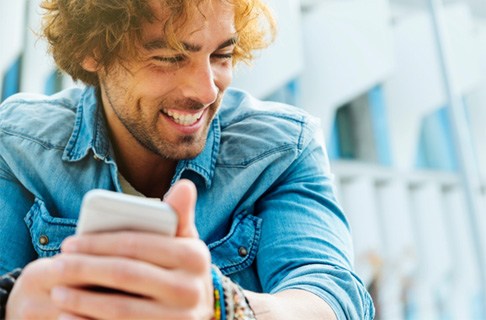 Man in denim jacket holding his phone