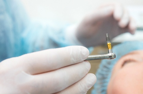 Periodontist preparing to place a dental implant in a patient’s mouth