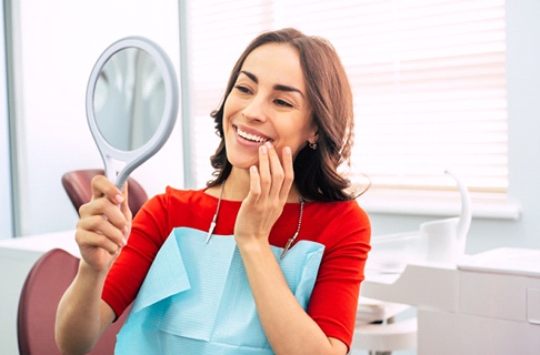 Dental patient using a mirror to admire her new smile