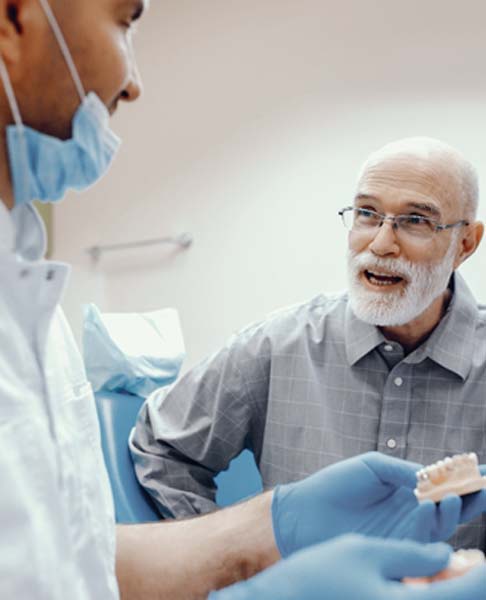 Man at a consultation while his dentist holds a model of the teeth