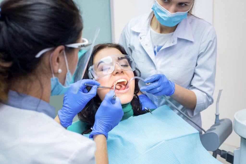 Two dentists performing surgery on woman with dark hair