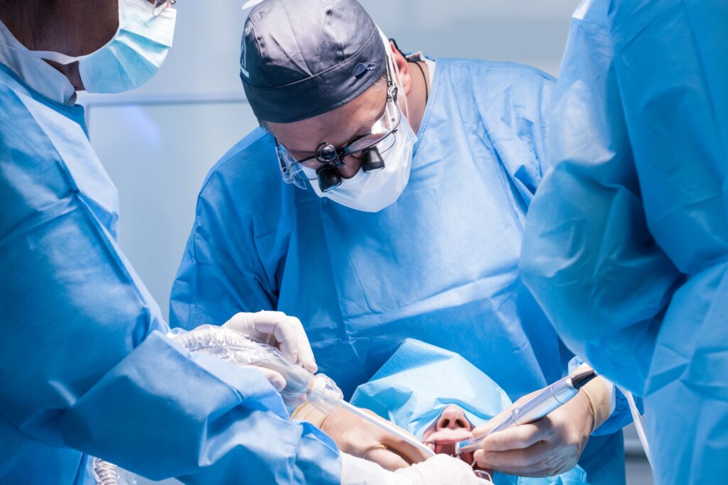Dentists in blue scrubs performing oral surgery on patient